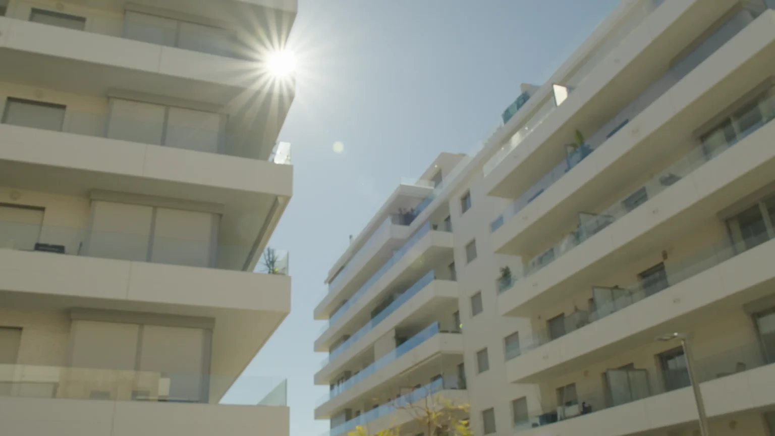 Vi erbjuder lägenhetsbesiktning i Marbella. Bilden föreställer några vita hus med balkonger i Marbella, under en klar himmel.